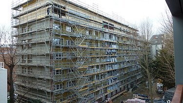 Photo of a multi-storey building in shell condition with a timber extension.