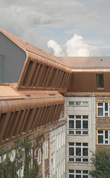 Foto der Holzaufstockung Metropolitan School Berlin. Zu sehen ist ein großes mehrgeschossiges Gebäude.