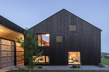 Foto eines modernen Holzhauses mit Holzfassade. Nachtaufnahme.