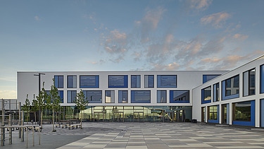 Exterior view of the Gymnasium München-Nord. You can see a large, white building with a flat roof.
