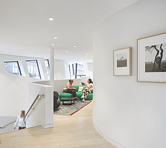 Photo of an interior. Two people are sitting on a green couch. 