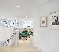 Photo of an interior. Two people are sitting on a green couch. 