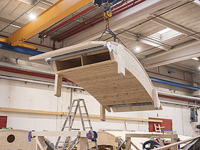 Foto einer Produktionshalle mit einer geschwungenen Holzschale am Kran