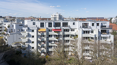Foto eines mehrgeschossigen Gebäudes mit weißer Fassade. Aufstockung aus Holz.