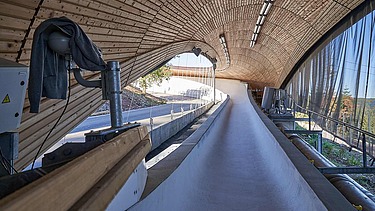 Foto einer Rodelbahn. Man sieht eine Holzüberdachung und nur einen Ausschnitt davon