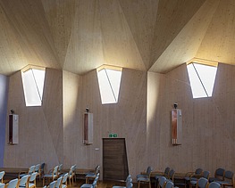 Foto eines Innenraums einer Kapelle mit großer gewölbter Holzdecke und Holzwänden