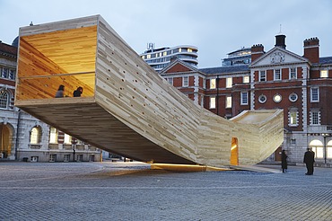 Photo of the curved wooden sculpture The Smile in London. The wooden box can be walked on and is intended to represent a smiling mouth.