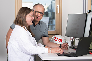 Foto von zwei Personen am PC-Arbeitsplatz. Ausbildung zur Industriekauffrau:mann.