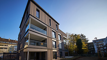 Foto eines mehrgeschossigen Wohngebäudes mit Holzfassade.