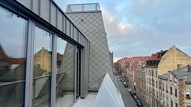 Foto einer Aufstockung aus Holz. Man sieht hoch oben ein Fensterdetail.