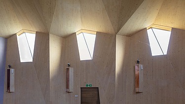 Foto eines Innenraums einer Kapelle mit großer gewölbter Holzdecke und Holzwänden