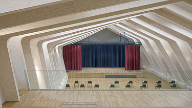 Foto eines Bühnenraumes mit großer sichtbarer Rippen-Holzkonstruktion.