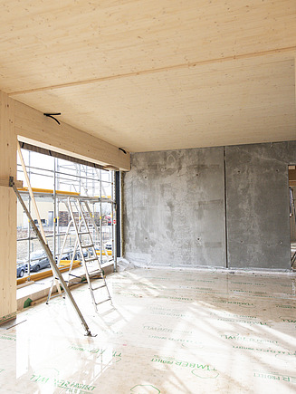Rohbaufoto eines Innenraums des Büro T3 in Aichach. Man sieht eine Holzdecke und Holzstützen.