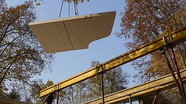 Foto eines am Kran schwebenden LENO-BSP-Elements für ein Wohnhaus.