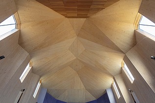 Foto eines Innenraums einer Kapelle mit großer gewölbter Holzdecke