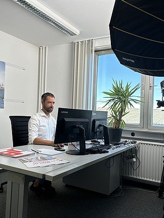 Photo of a movie scene. You can see a man working at a PC workstation.