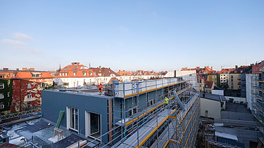 Photo of the VINZENT building shell in Munich. You can see a scaffolded, multi-storey building.