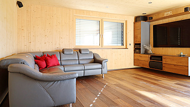 Foto eines Wohnhauses aus LENO-Brettsperrholz. Wohnzimmer mit vielen Holzoberflächen.