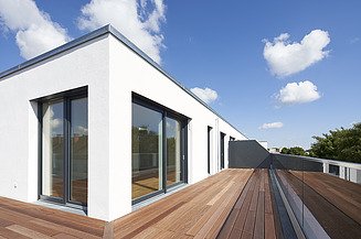 Additions, building in existing buildings. Bodenehrstraße extension project Munich Photo of a wooden building with a white façade. You can see a close-up of the extension with wooden terrace.