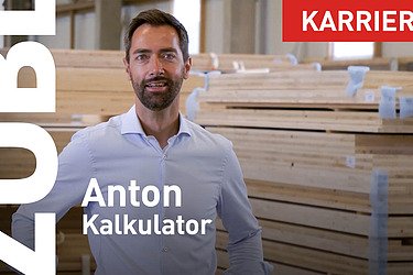 Foto von einem Mann, Holzstapel im Hintergrund.