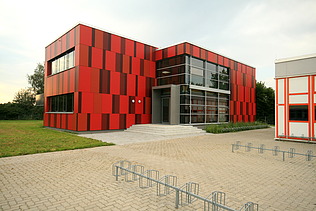Foto einer Außenansicht der Einhardschule in Seligenstadt. Man sieht eine rote Fassade.