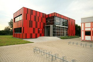 Photo of an exterior view of the Einhard School in Seligenstadt. You can see a red facade.