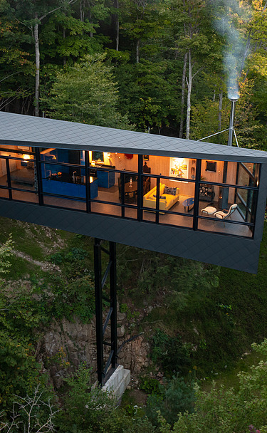 Foto eines Wohnhauses aus Holz auf Stahlpfählen, inmitten des Waldes.