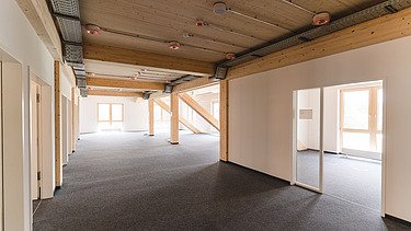 Photo of the inside of Witten University. You can see an interior with light-colored walls and a wooden ceiling