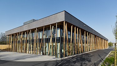 Foto eines Hauses mit Flachdach und vorgelagerten Staketen aus einer verglasten Pfosten-Riegel-Konstruktion.