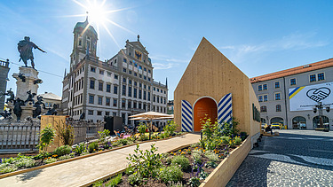 Foto des NEXT500-Pavillons auf dem Augsburger Marktplatz. Sie können ein modernes Holzgebäude sehen.