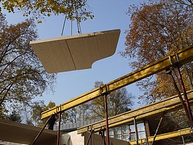 Foto eines am Kran schwebenden LENO-BSP-Elements für ein Wohnhaus.