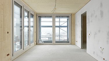 Foto des Gebäudes SKAIO Stadtsiedlung in Heilbronn. Man sieht einen Innenraum  mit Holzoberflächen und Betonwand.