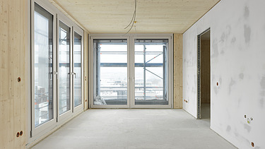 Photo of the SKAIO Stadtsiedlung building in Heilbronn. You can see an interior with wooden surfaces and a concrete wall.