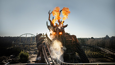Photo of the Colossos wooden roller coaster at Heide Park Resort Soltau. You can see a fire-breathing wooden dragon and part of the roller coaster.