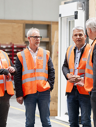 Fünf Männer, die sich in der Fertigungshalle von ZÜBLIN Timber unterhalten.