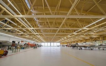 Foto der Montagehalle Pilatus CH-Stans. Zu sehen ist eine große Brettschichtholz-Dachkonstruktion.