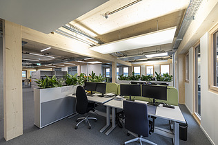 Innenraumfoto des Büroneubaus T3 in Aichach. Zu sehen sind Bildschirmarbeitsplätze.