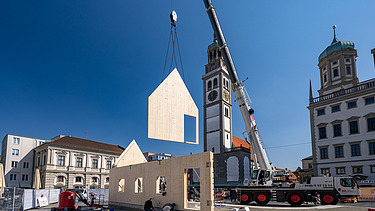 Foto des NEXT500-Pavillons auf dem Augsburger Marktplatz. Sie können die Montage der LENO-Elemente sehen.