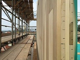 Photo of a LENO cross-laminated timber wall. Side cross-section. Assembly photo with scaffolding.