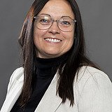 Foto von einer Frau mit langen braunen Haare und Brille. Michaela Dumbs.