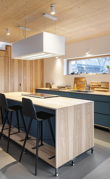 Foto eines Küchenwohnraumes mit sichtbarer LENO-Brettsperrholzdecke.