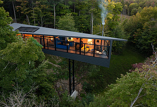 Foto eines Wohnhauses aus Holz auf Stahlpfählen, inmitten des Waldes.