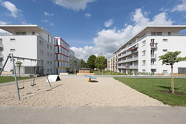 Aufstockung Konradsiedlung, Regensburg Foto zweier mehrgeschossigen Gebäude mit Garten davor. Aufstockungen aus Holz.