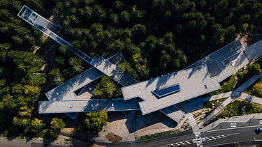 Timber engineering and free-form surfaces from ZÜBLIN Timber. Ruhestein visitor center project Aerial view of the visitor center in Ruhestein. You can see a building complex in the middle of a forest.