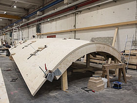 Foto einer Produktionshalle mit einer geschwungenen Holzschale