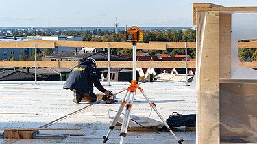 Foto der Montage des UmweltHauses in Nürnberg. Man sieht eine Person, die Messaufnahmen macht.