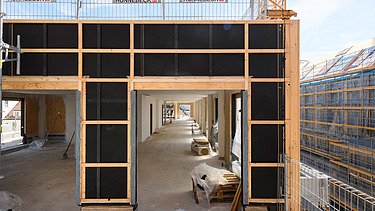 Photo of the VINZENT building shell in Munich. A timber frame construction element can be seen.