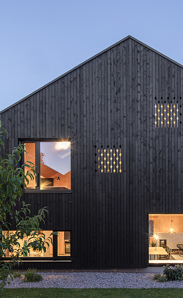 Foto eines modernen Holzhauses mit Holzfassade. Nachtaufnahme.