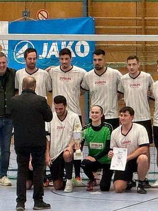 Teamfoto einer Hobby-Fußballmannschaft in einer Sporthalle.