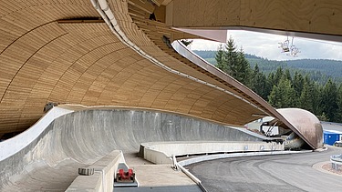 Foto einer Rodelbahn. Man sieht eine Holzüberdachung und nur einen Ausschnitt davon